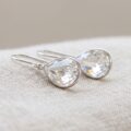 Elegancka para kolczyków Swarovski z kryształami na neutralnym, jasnym tle – widok z bliska ukazujący grę światła w kryształach
